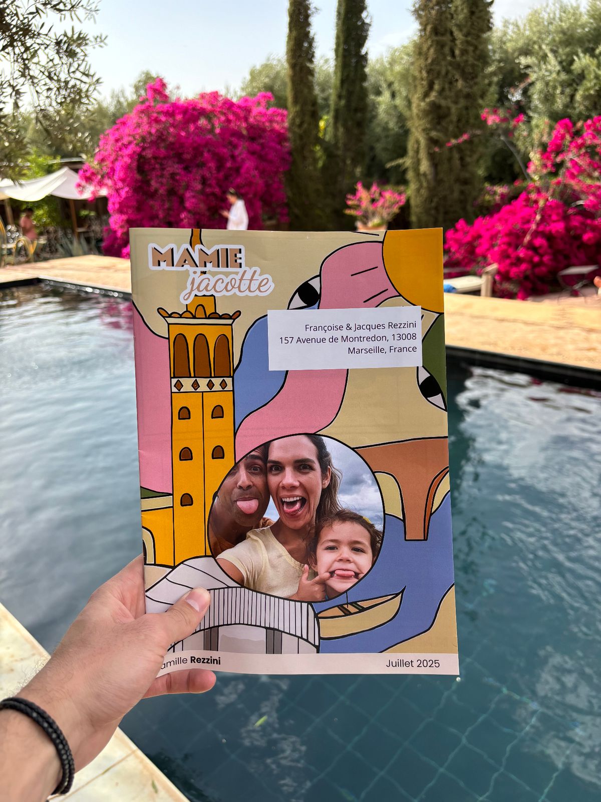 Magazine Mamie Jacotte tenu devant une piscine fleurie